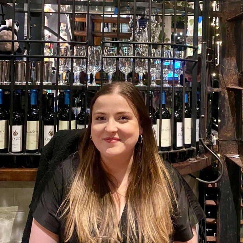 Picture of Peigidh Savage, Media, Marketing and Sales, sitting in front of a wine rack in a restaurant